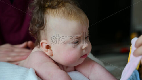 Infant lifting head during tummy time while caregiver supports gently