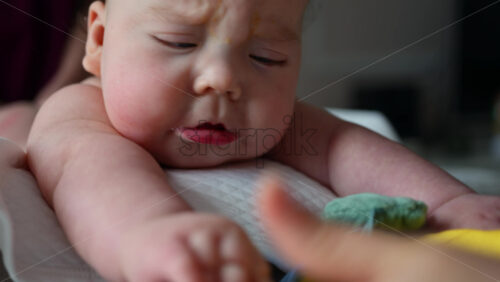Baby focusing on colorful soft toy during a massage