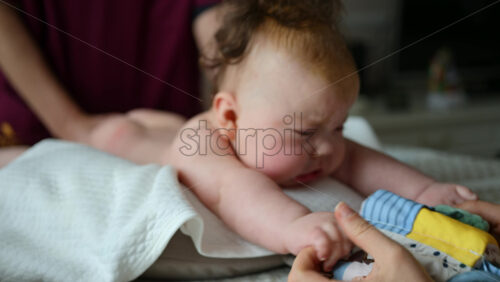 Baby focusing on colorful soft toy during a massage