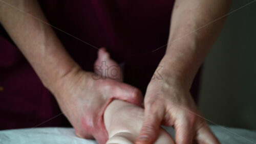 Close up of adult hands gently massaging a baby's foot and sole