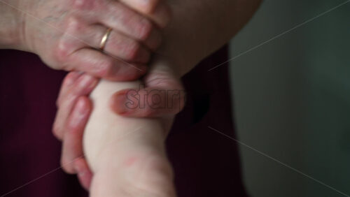 Close up of adult hands gently massaging a baby's foot and sole