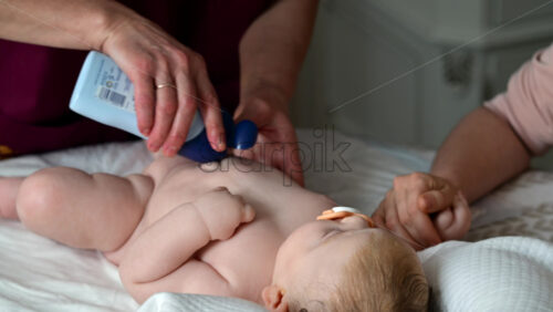Baby lying on their back while an adult massages them and the mother gently holds the baby's hand