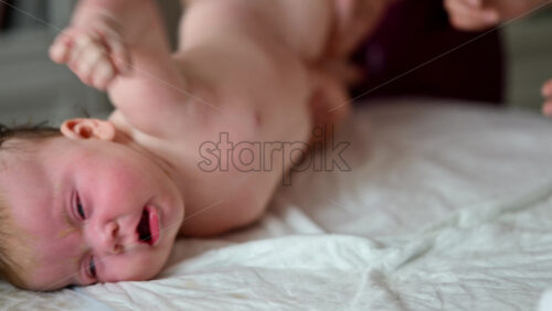 Baby lying on their back while an adult massages them and performs mobility exercises