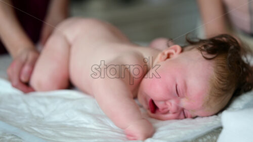 Baby lying on their tummy while an adult massages them and performs mobility exercises