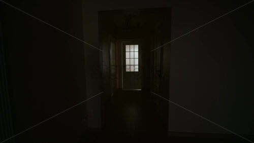 Camera moving towards soft light glowing through a frosted glass door in a dark interior hallway