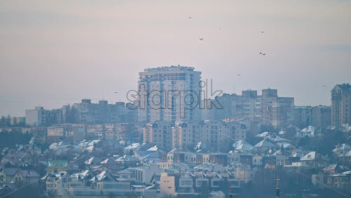 Wide residential cityscape with layered apartment buildings and houses under soft morning haze