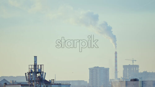 City rooftops on a cold winter day with multiple chimneys releasing white smoke into a pale sky