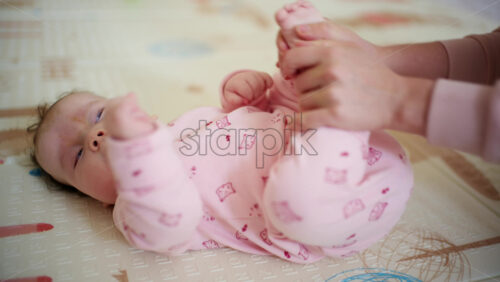 Infant lying on back while a caregiver gently holds and moves the baby's legs