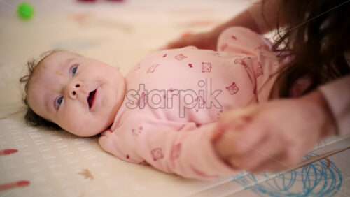 Caregiver holding the baby's arm upright to support movement
