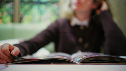 Young woman reading an open menu at a table indoors
