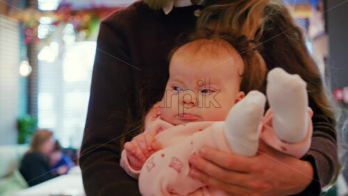 Mother holding a baby in her arms inside a restaurant