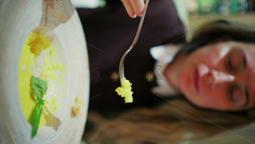 Close up of a woman eating risotto with greens at a restaurant. Vertical