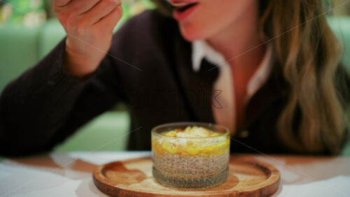 Woman eating a chia pudding in a glass cup using a spoon