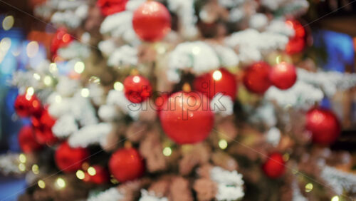 Decorated Christmas tree with red ornaments, snow covered branches, and soft glowing lights in the background