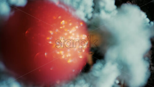 Close up of a decorated Christmas tree with red ornaments, snow covered branches, and soft glowing lights in the background
