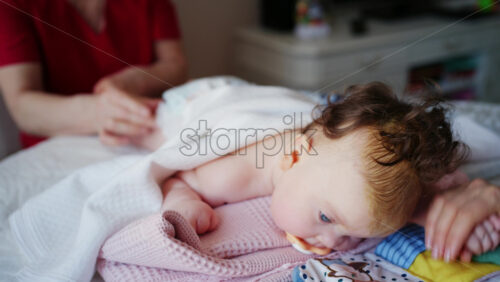 Baby lying on their tummy while an adult massages them and performs mobility exercises