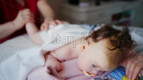 Baby lying on their tummy while an adult massages them and performs mobility exercises