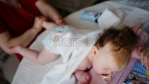 Baby lying on their tummy while an adult massages them and performs mobility exercises