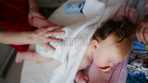 Baby lying on their tummy while an adult massages them and performs mobility exercises