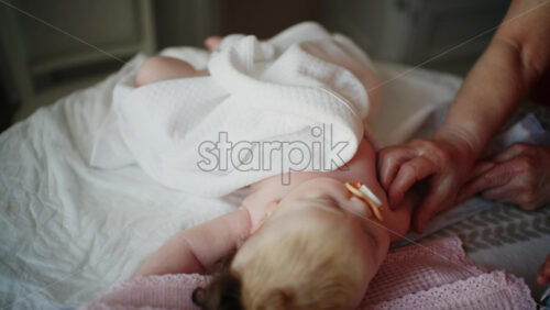 Baby lying on their back while an adult massages them and the mother holds the pacifier in the baby's mouth
