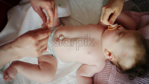 Baby lying on their back while an adult massages them and the mother holds the pacifier in the baby's mouth