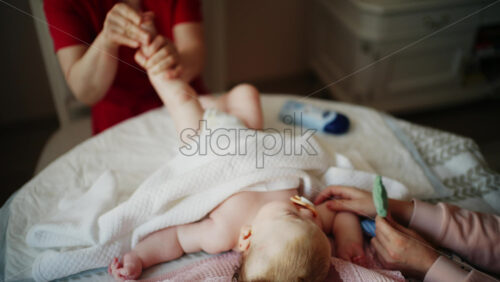 Infant on back with a pacifier while caregivers gently massages the baby's feet
