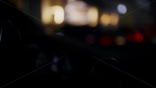 Night driving scene from inside a car with steering wheel and dashboard visible