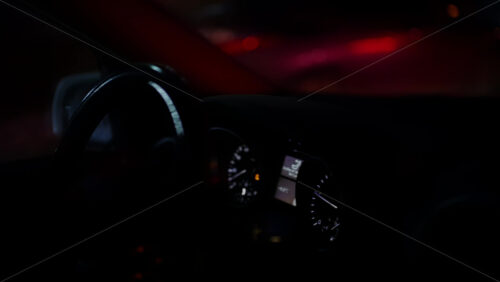 Close view of a car dashboard and instrument cluster at night, partially seen through the steering wheel