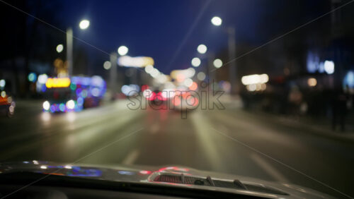 Forward facing night drive along a city street with headlights and streetlights blurred