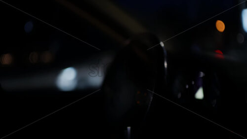 Close view of a car dashboard and instrument cluster at night, partially seen through the steering wheel