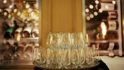Elegant wine glasses arranged on a tray in a softly lit restaurant setting, with wine racks blurred in the background