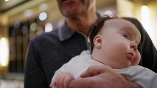 Middle aged man holding a baby in a warmly lit restaurant interior