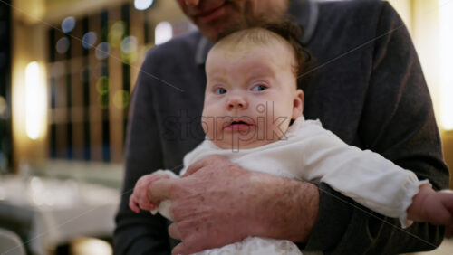 Middle aged man holding a baby in a warmly lit restaurant interior