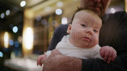 Middle aged man holding a baby in a warmly lit restaurant interior