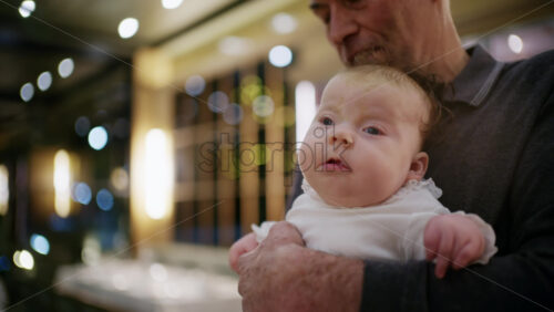 Middle aged man holding a baby in a warmly lit restaurant interior
