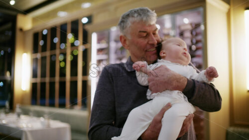 Middle aged man holding a baby in a warmly lit restaurant interior