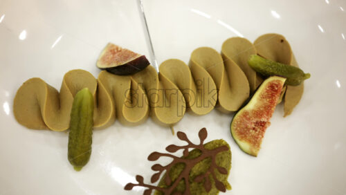 Gourmet plated dish with artistic presentation, featuring figs and decorative elements on a white plate