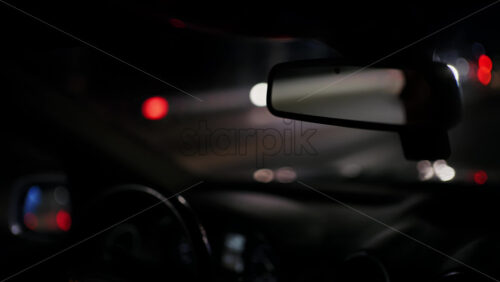 Close perspective of a car interior at night with dashboard details and windshield reflections