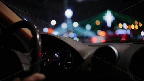 View from inside a car of a night city street with illuminated decorative lights in the distance