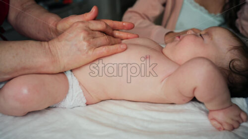 Infant lying on the back while a caregiver gently massages the baby's upper body