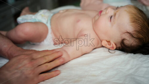 Close up of adult hands gently massaging a baby's arm and palm