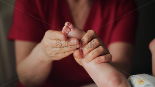 Close up of adult hands gently massaging a baby's foot and sole