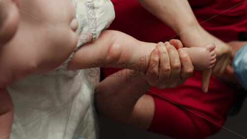 Close up of adult hands gently massaging a baby's foot and sole