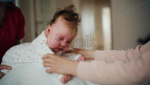 Baby placed on tummy on a stability ball while adults support the infant's torso and shoulders