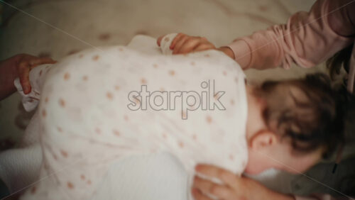 Baby placed on tummy on a stability ball while adults support the infant's torso and shoulders