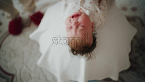 Baby placed on the back on a stability ball while adults support the infant's torso and shoulders