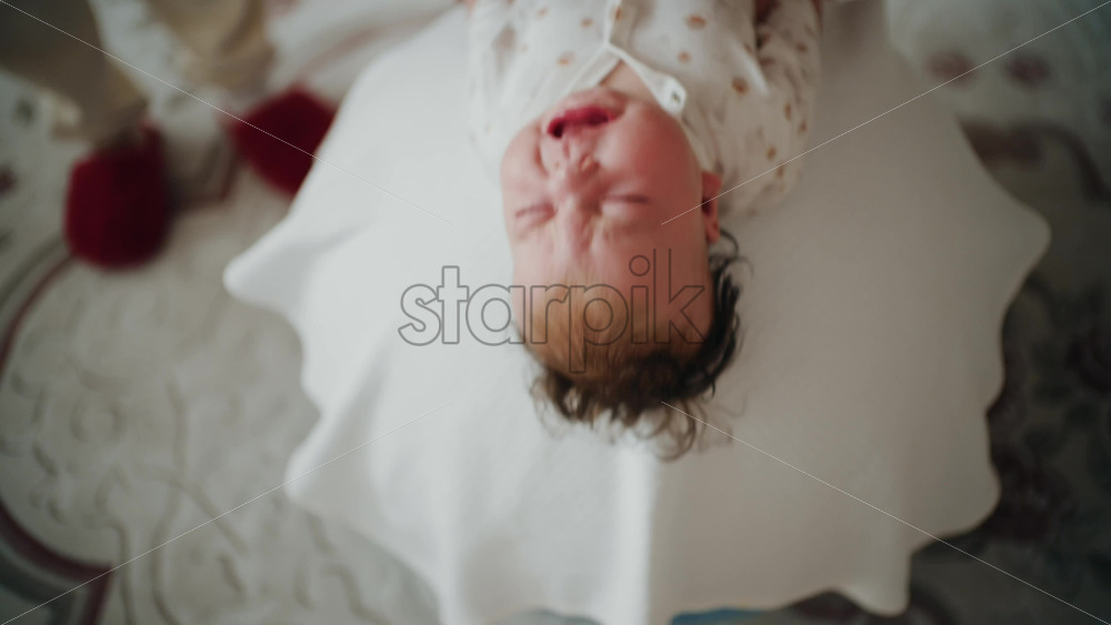 Baby placed on the back on a stability ball while adults support the infant's torso and shoulders