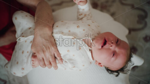 Baby placed on the back on a stability ball while adults support the infant's torso and shoulders