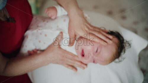 Baby placed on the back on a stability ball while adults support the infant's torso and shoulders