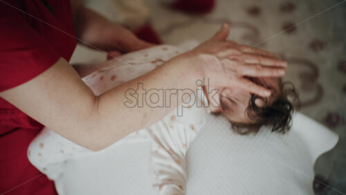 Baby placed on the back on a stability ball while adults support the infant's torso and shoulders